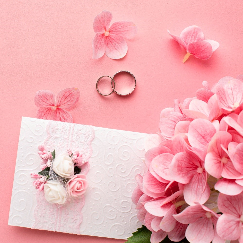 Wedding Card Wedding invitation card with pink flowers and two rings on a soft pink background.